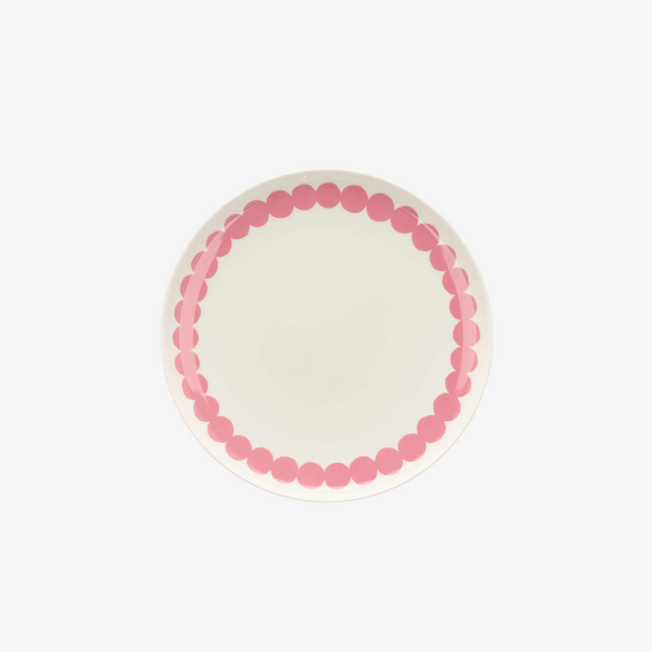 A round white plate with a decorative border of pink polka dots, photographed from directly above on a clean white background.