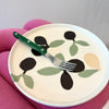 Plate with olive design and fork on a pink surface
