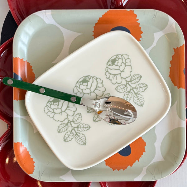 Decorative plate with floral design and spoon on a red and white background