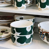 Set of green and white floral-patterned ceramic dishes on a shelf.