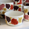 Set of ceramic bowls and mugs with floral pattern on a neutral background