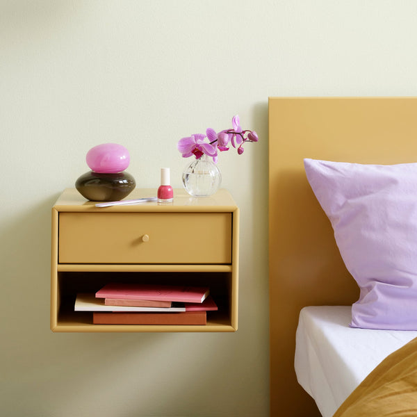 Nighstand with decorative items next to a bed with a pillow