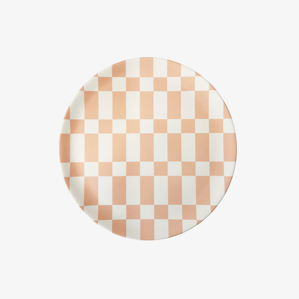 A round ceramic plate featuring a checkered pattern of peach and white squares, centered on a light gray background.