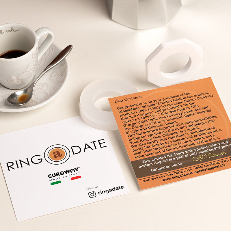 Two business cards on a table with a cup of coffee and saucer.