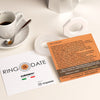 Two business cards on a table with a cup of coffee and saucer.