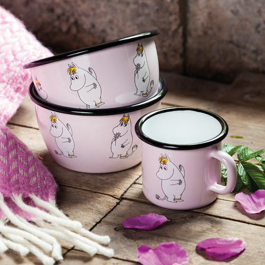 Set of pink enamel mugs with cartoon character on a wooden surface with pink petals.