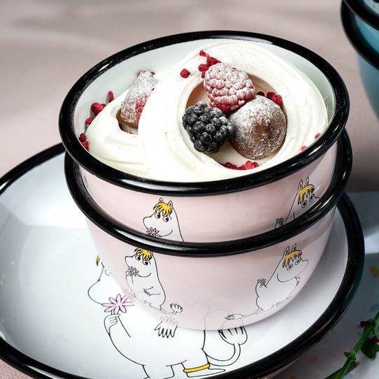 Two-tiered dessert with whipped cream and berries in a pink container with cartoon characters on a light background.
