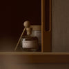 Clear glass bottle with wooden spray nozzle on a wooden shelf against a brown background