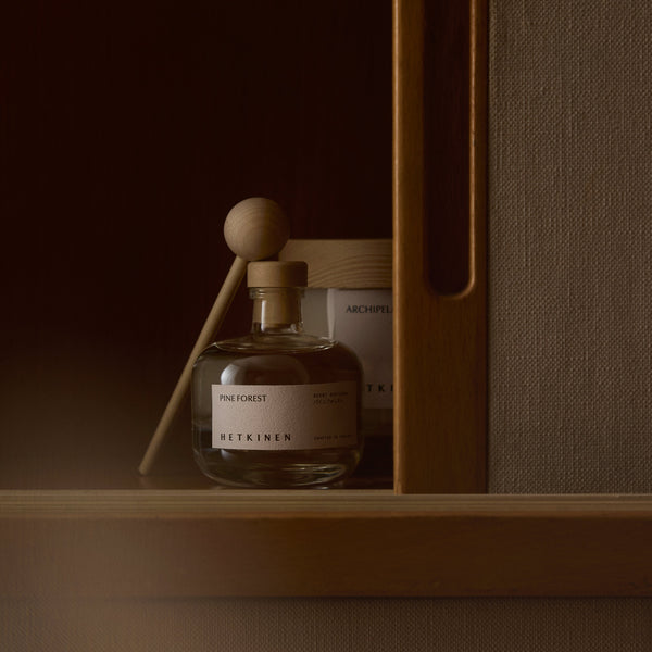 Clear glass bottle with wooden spray nozzle on a wooden shelf against a brown background